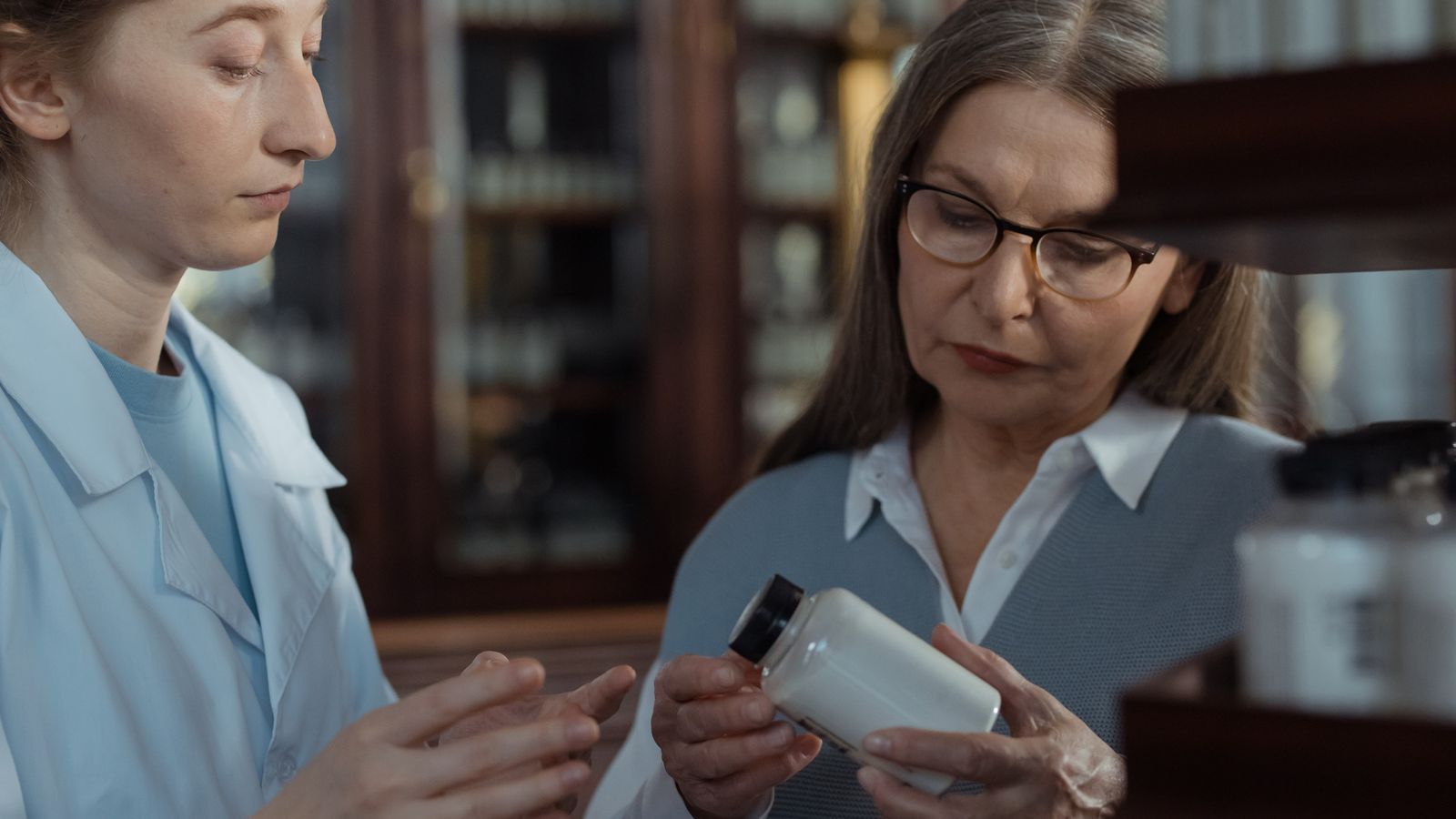 Pharmacist advising an older patient holding a bottle of medicine