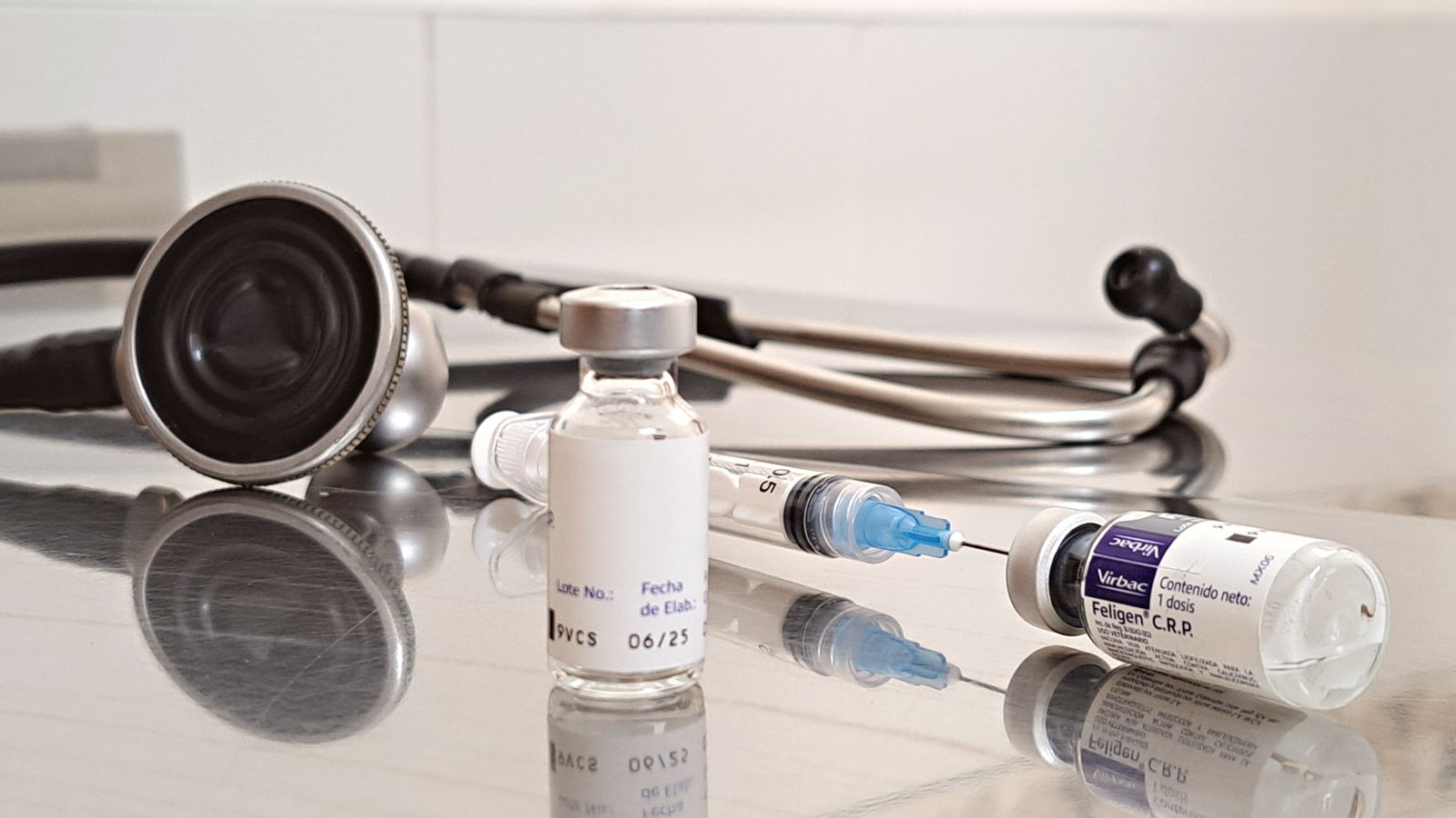Vaccine vials and syringes on a bench beside a stethoscope