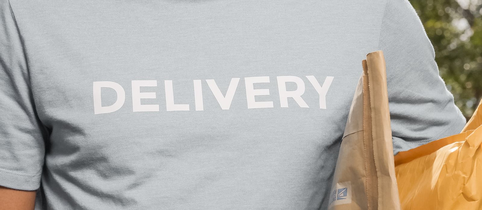 A delivery worker in a Delivery shirt holding parcels