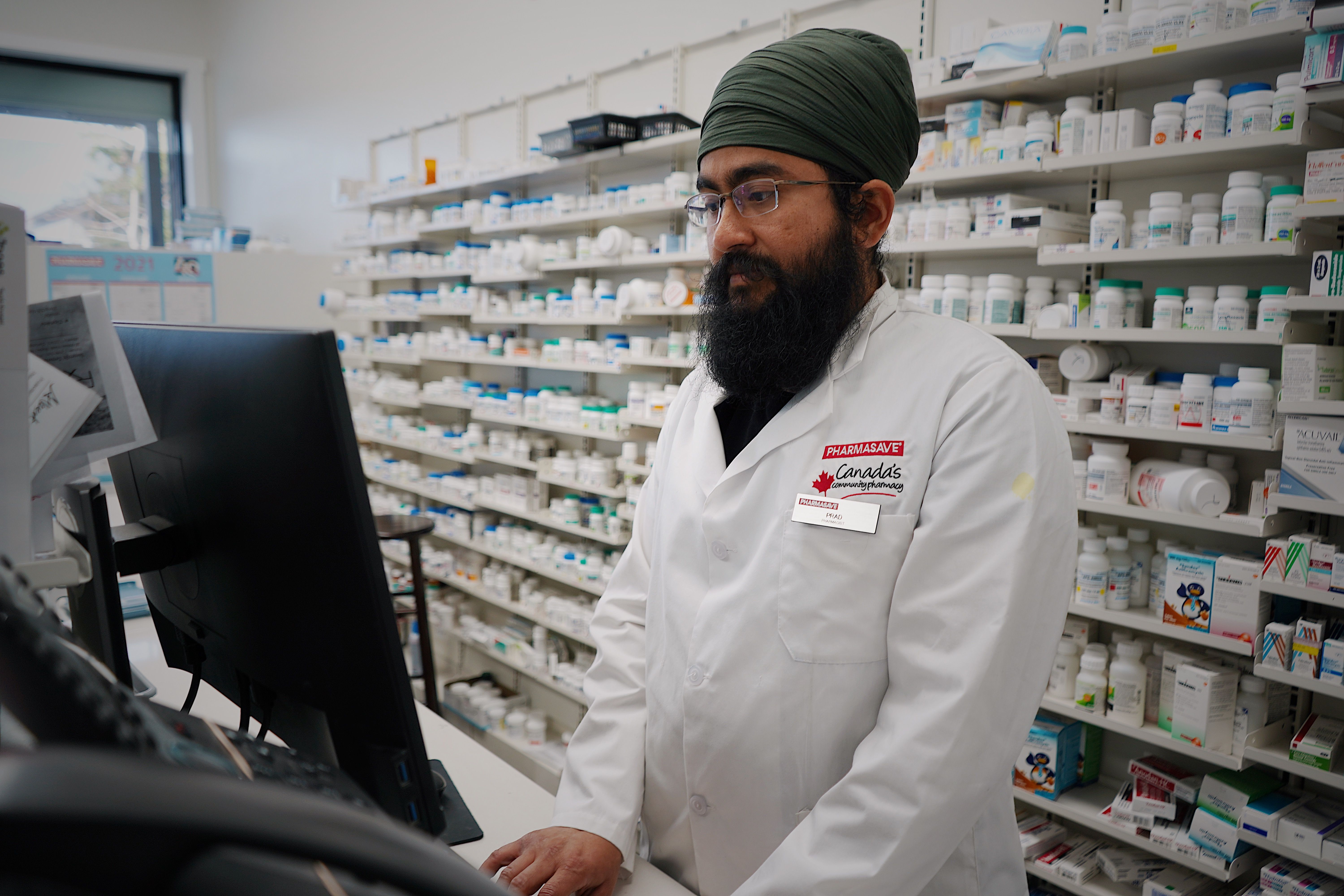 Pharmacist using dispense software at a pharmacy counter