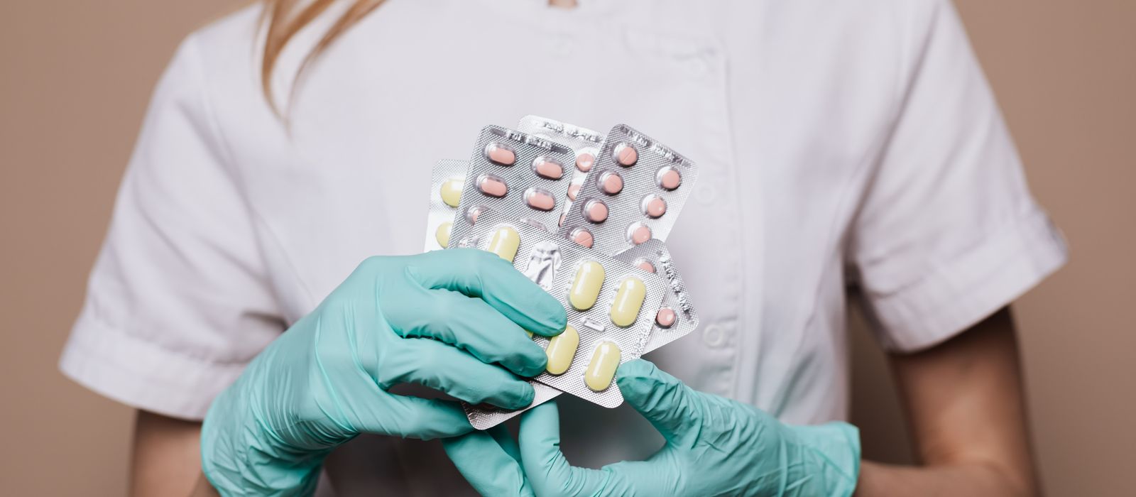 Gloved hands holding blister packs of medicine