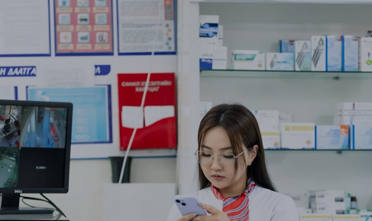 Pharmacist reviewing a mobile message in a pharmacy