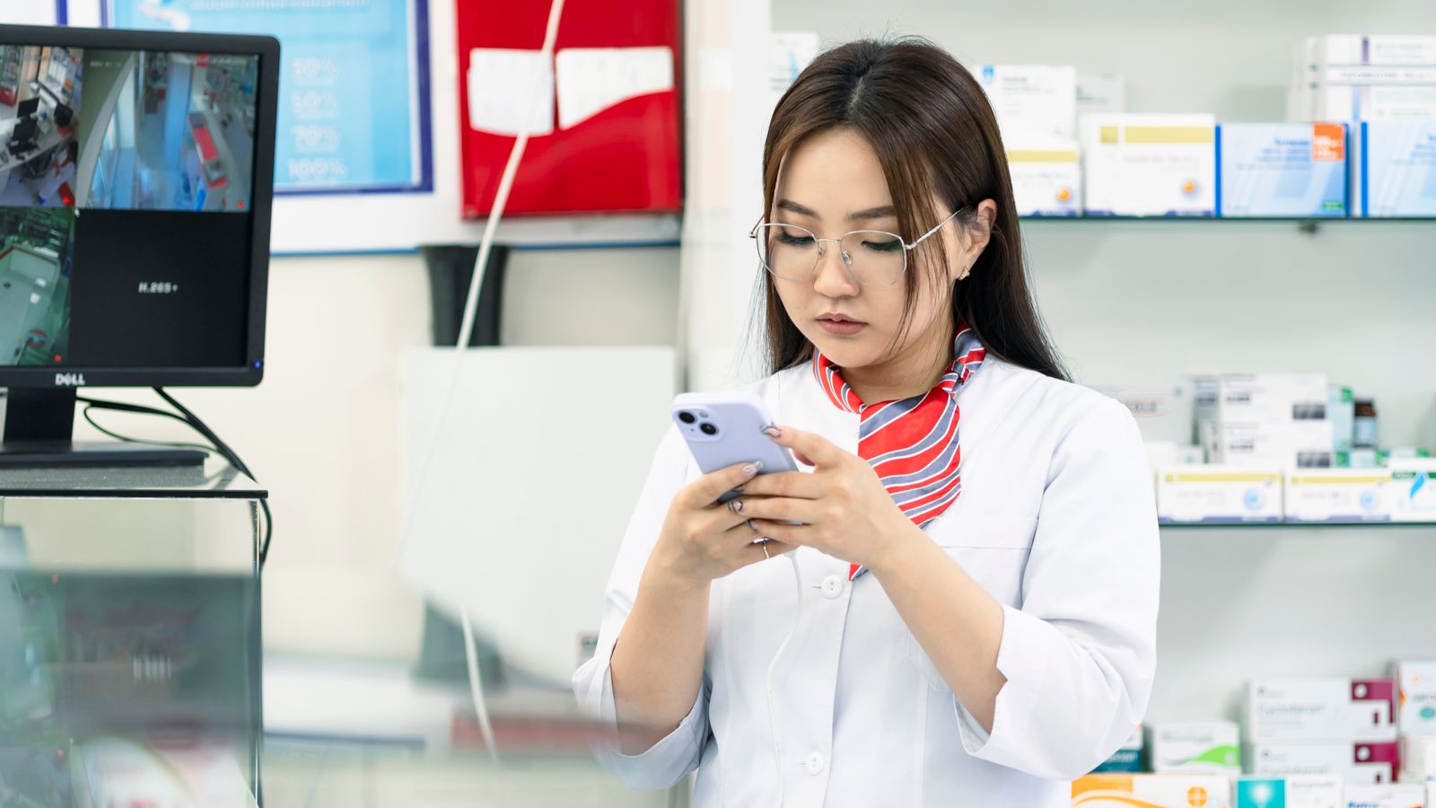 Pharmacy worker on her own behind the counter of a community pharmacy