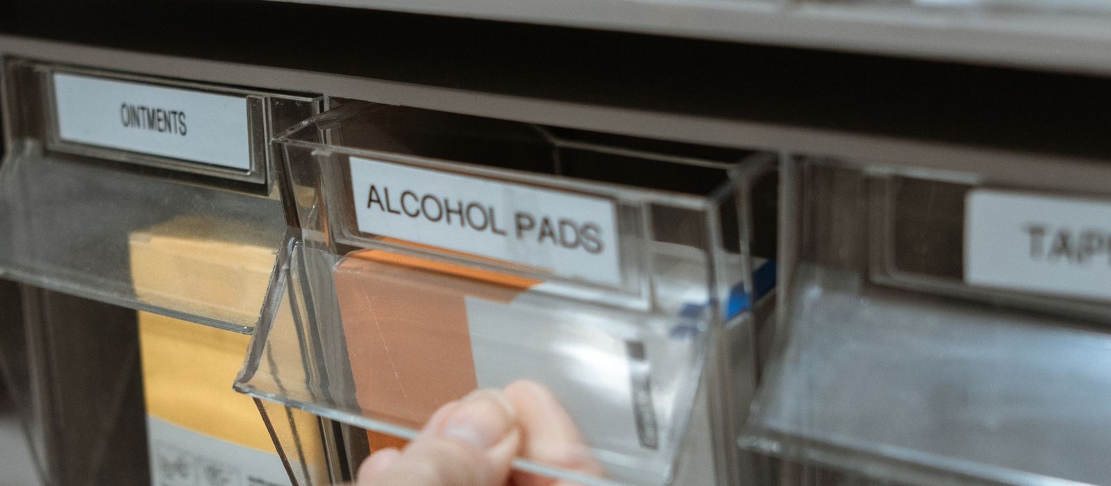Labelled pharmacy stock bins on a shelf