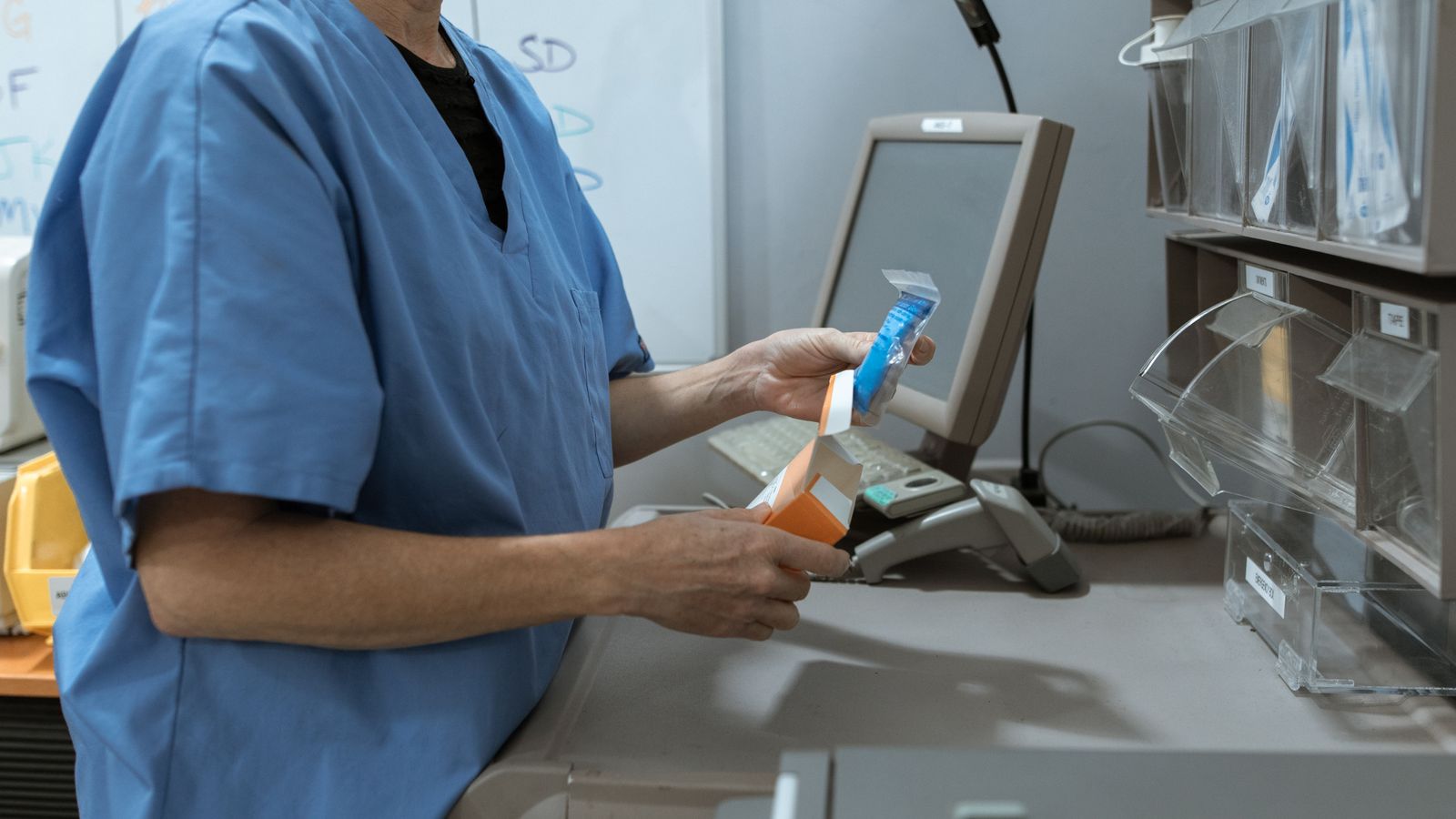 Pharmacy staff member checking a medicine box at the dispensing bench