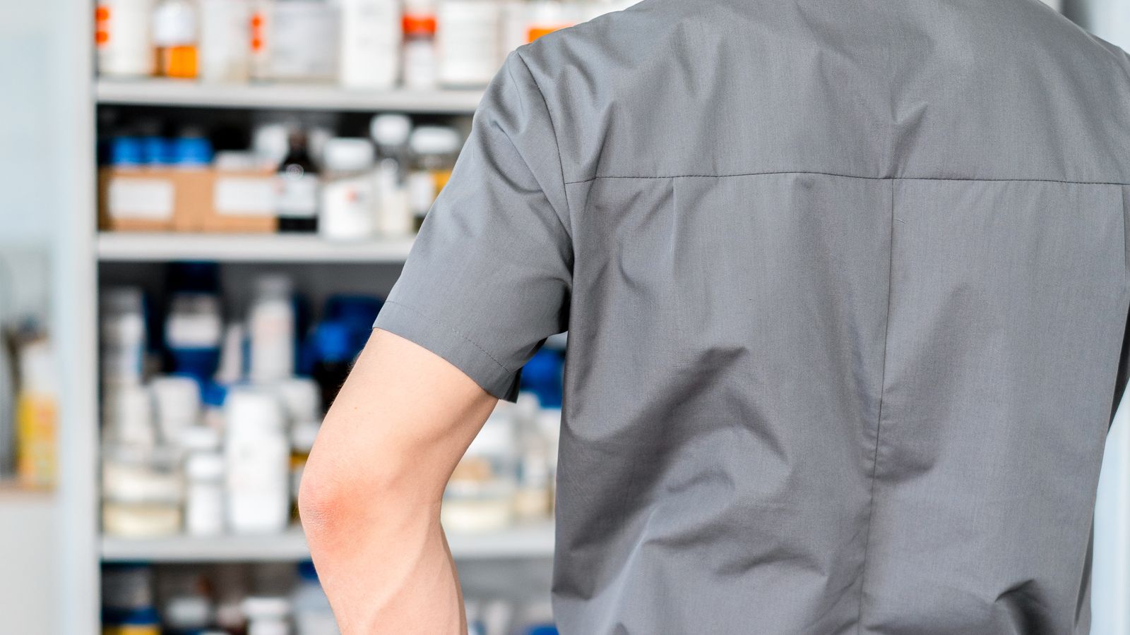 A pharmacist working at the dispensing shelves
